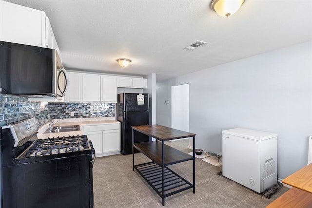 kitchen with black appliances, white cabinetry, sink, and tasteful backsplash