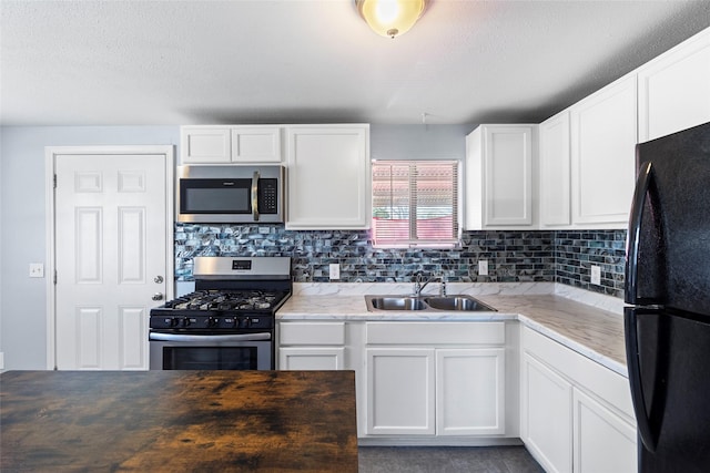 kitchen with decorative backsplash, sink, white cabinets, and stainless steel appliances