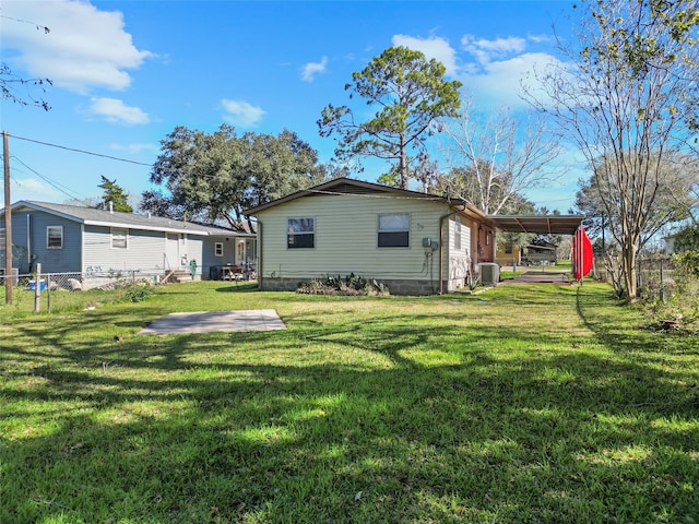 back of property featuring a carport, a yard, and central AC