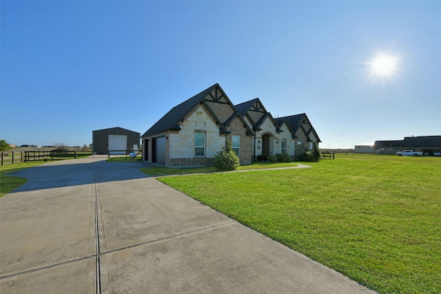 french country inspired facade featuring a garage, an outdoor structure, and a front lawn