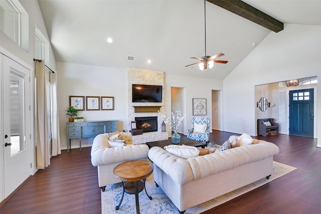 living room featuring a stone fireplace, dark hardwood / wood-style floors, high vaulted ceiling, beamed ceiling, and ceiling fan