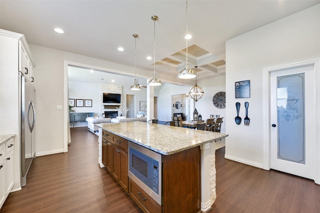 kitchen with coffered ceiling, white cabinetry, decorative light fixtures, appliances with stainless steel finishes, and a kitchen island