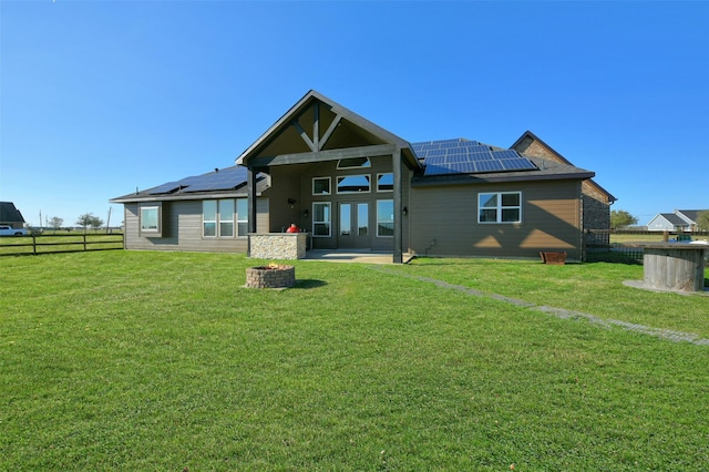 back of house featuring a patio, a lawn, and solar panels