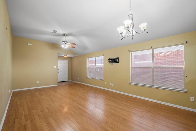 spare room with ceiling fan with notable chandelier, light hardwood / wood-style flooring, and vaulted ceiling