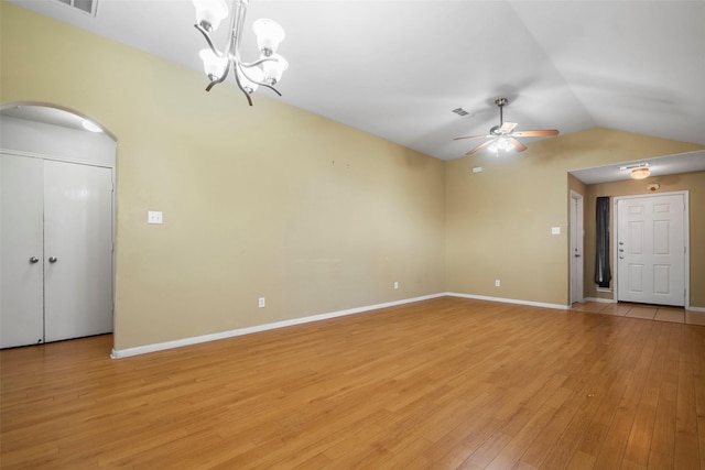 unfurnished living room with ceiling fan with notable chandelier, light wood-type flooring, and vaulted ceiling