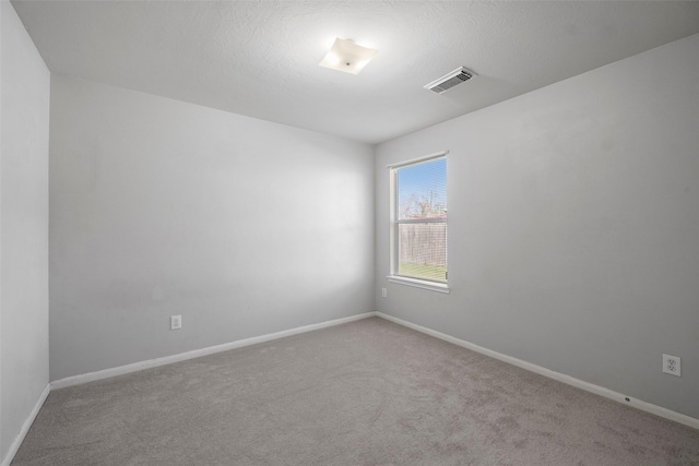 spare room with light colored carpet and a textured ceiling