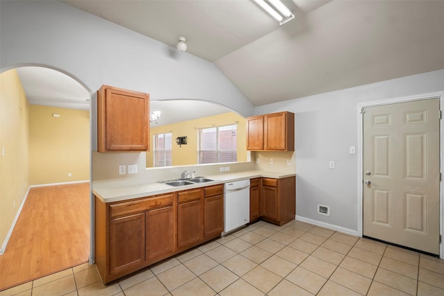 kitchen with white dishwasher, light tile patterned floors, sink, and vaulted ceiling