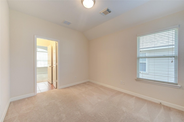 carpeted spare room with vaulted ceiling