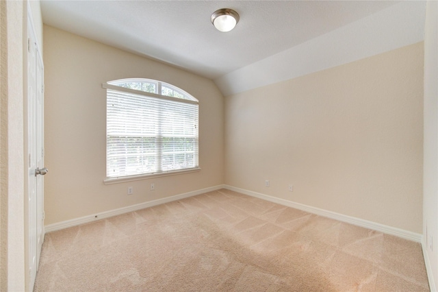 carpeted empty room featuring vaulted ceiling