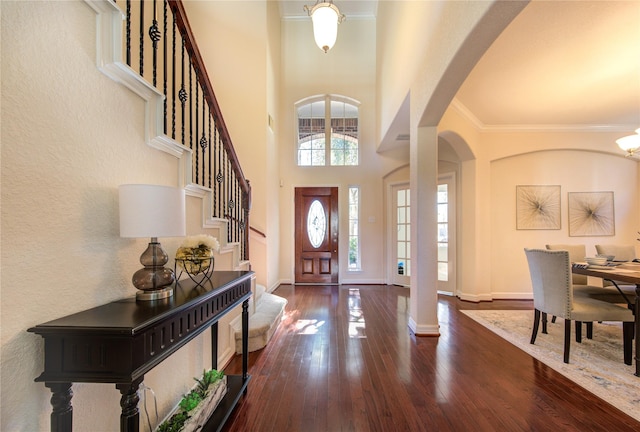 entrance foyer featuring a high ceiling, dark wood-type flooring, ornate columns, and ornamental molding