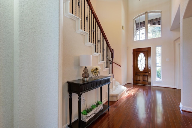 foyer entrance with dark hardwood / wood-style flooring and a towering ceiling