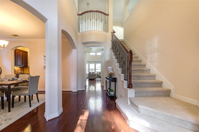 foyer entrance featuring dark hardwood / wood-style flooring, crown molding, and a high ceiling