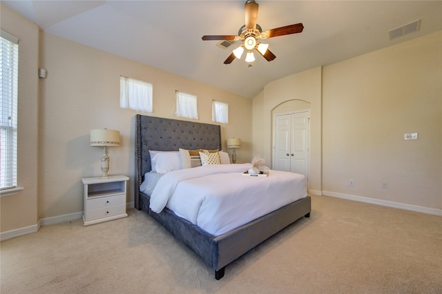 bedroom featuring ceiling fan, lofted ceiling, multiple windows, light carpet, and a closet