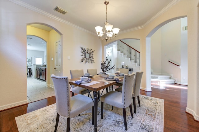 dining area featuring crown molding, hardwood / wood-style floors, and a chandelier