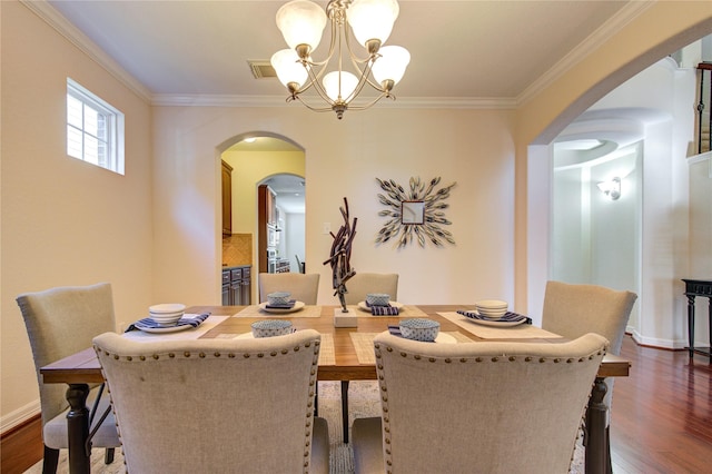 dining area with dark hardwood / wood-style flooring, an inviting chandelier, and ornamental molding