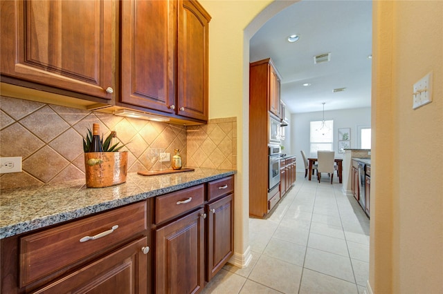 kitchen with decorative backsplash, light stone countertops, light tile patterned floors, and pendant lighting