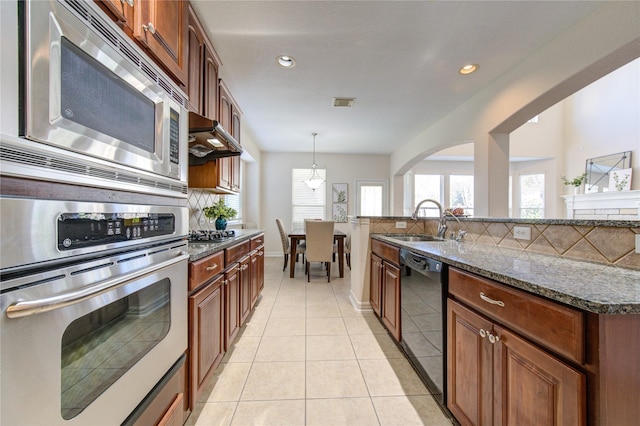 kitchen with pendant lighting, sink, dark stone countertops, appliances with stainless steel finishes, and light tile patterned flooring