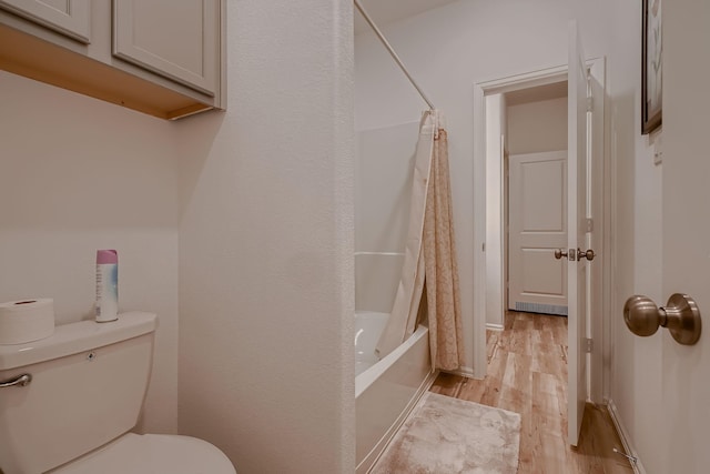 bathroom with hardwood / wood-style floors, shower / bath combo, and toilet