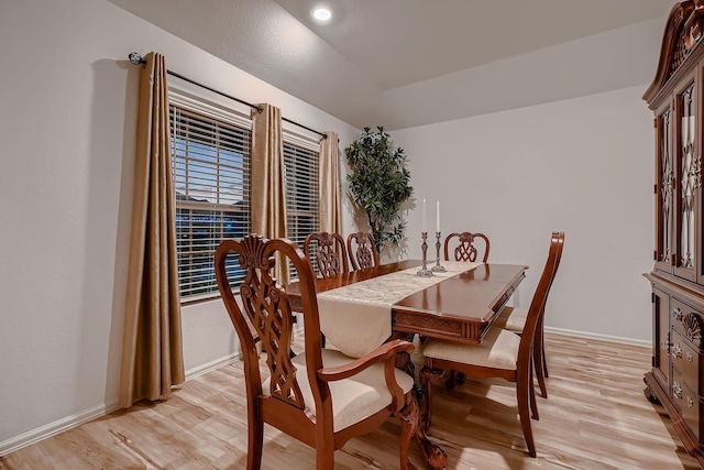 dining space with vaulted ceiling and light hardwood / wood-style flooring