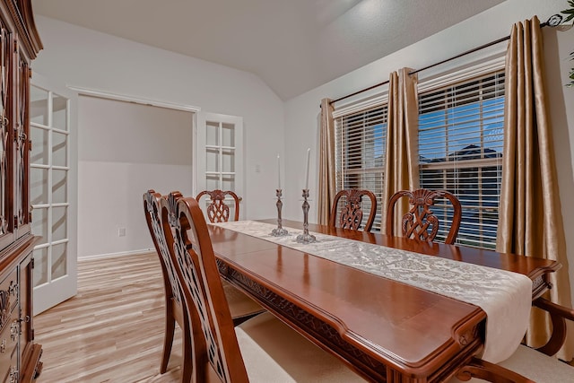 dining room with french doors, light hardwood / wood-style floors, and vaulted ceiling