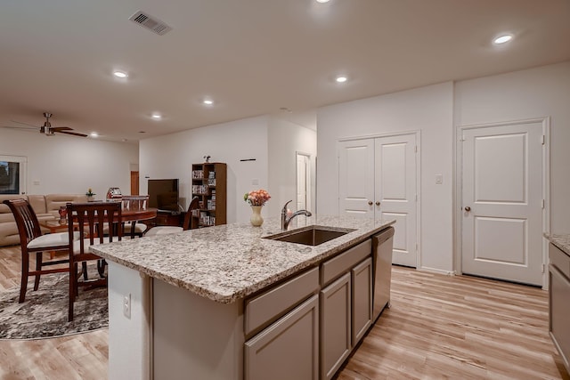 kitchen with gray cabinetry, sink, stainless steel dishwasher, ceiling fan, and an island with sink