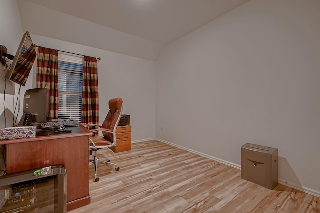 home office with light hardwood / wood-style floors and vaulted ceiling