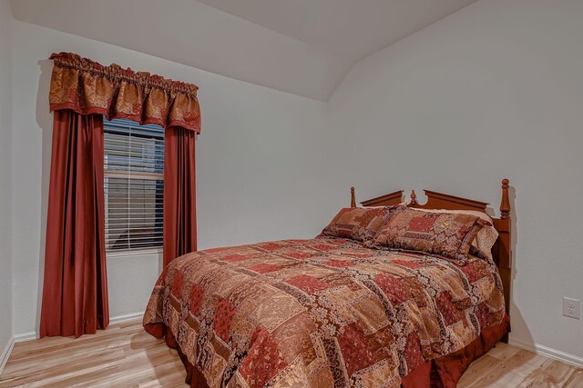 bedroom with light hardwood / wood-style floors and lofted ceiling