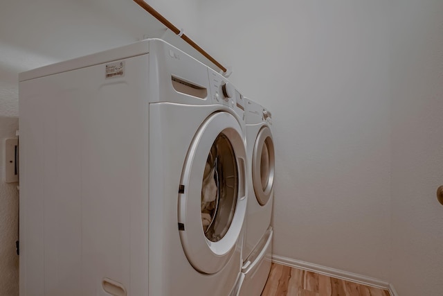 laundry room with washer and dryer and light hardwood / wood-style floors