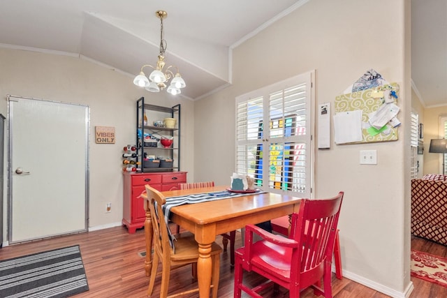 dining space featuring hardwood / wood-style flooring, a notable chandelier, crown molding, and vaulted ceiling