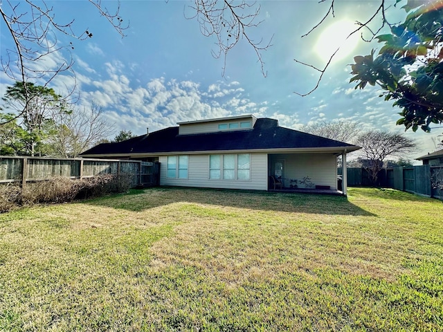 back of house with a fenced backyard and a yard