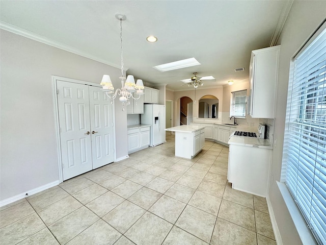 kitchen with white cabinets, a kitchen island, light countertops, white fridge with ice dispenser, and pendant lighting