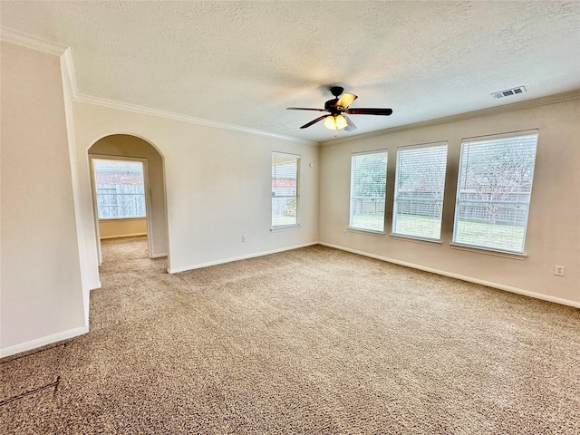 spare room featuring visible vents, arched walkways, baseboards, carpet, and crown molding