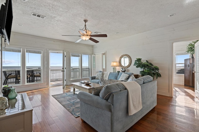 living room featuring ceiling fan, wood walls, and dark hardwood / wood-style flooring