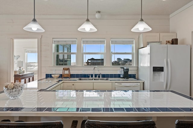 kitchen with pendant lighting, white appliances, and sink