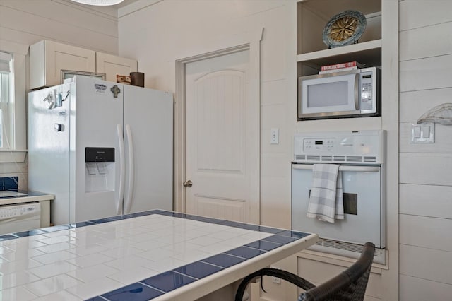 kitchen featuring tile counters and white appliances