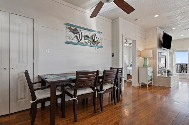 dining space with dark hardwood / wood-style flooring, a textured ceiling, ceiling fan, and wood walls