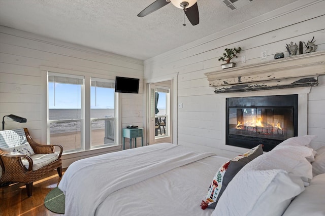 bedroom featuring hardwood / wood-style flooring, ceiling fan, a textured ceiling, and wooden walls