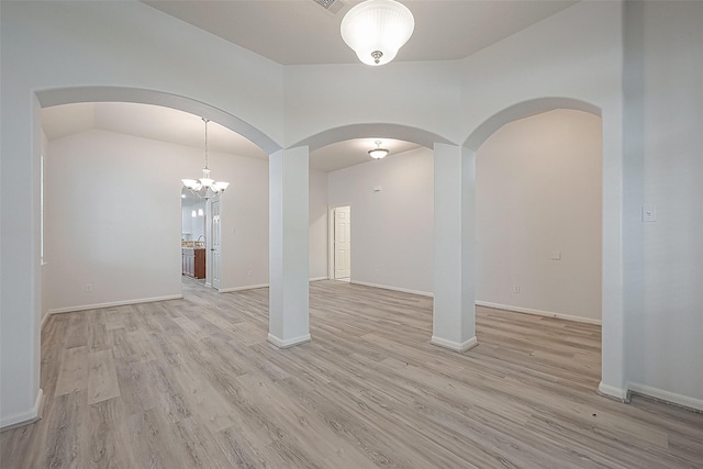 spare room with a notable chandelier and light hardwood / wood-style floors