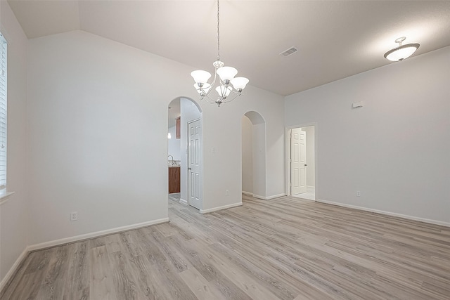 unfurnished room with a notable chandelier, vaulted ceiling, and light hardwood / wood-style flooring