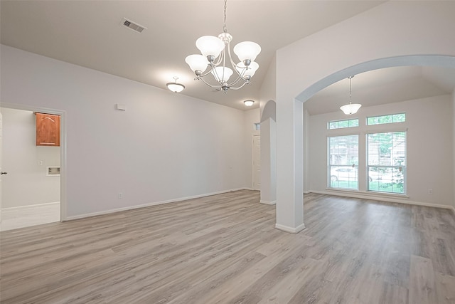 empty room with an inviting chandelier, lofted ceiling, and light hardwood / wood-style flooring