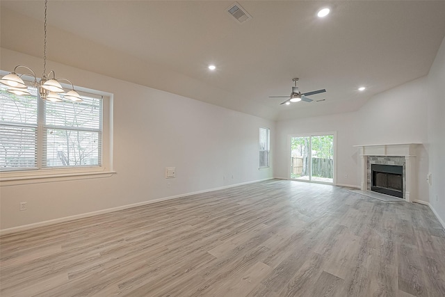 unfurnished living room featuring ceiling fan with notable chandelier, light hardwood / wood-style floors, a fireplace, and vaulted ceiling