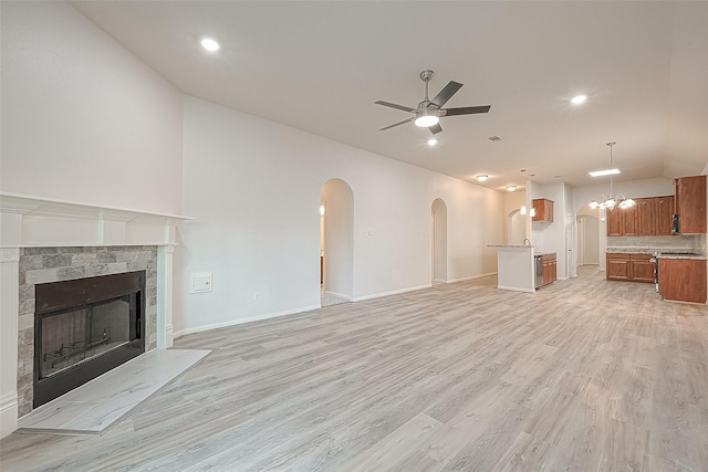 unfurnished living room featuring light hardwood / wood-style floors, a stone fireplace, and ceiling fan