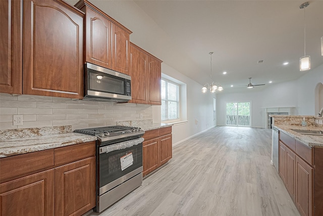 kitchen featuring ceiling fan with notable chandelier, sink, decorative backsplash, decorative light fixtures, and stainless steel appliances