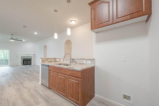 kitchen with ceiling fan, dishwasher, light stone countertops, sink, and decorative light fixtures