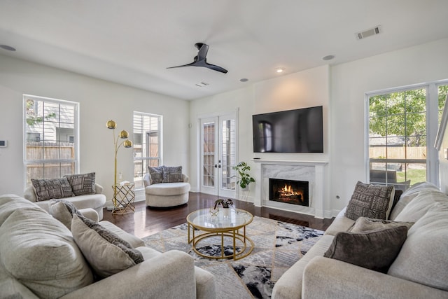 living room featuring wood-type flooring, french doors, ceiling fan, and a premium fireplace