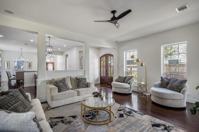 living room with ceiling fan with notable chandelier, dark hardwood / wood-style flooring, and french doors