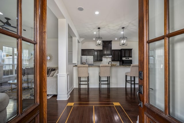 kitchen featuring decorative columns, a breakfast bar, dark hardwood / wood-style floors, and appliances with stainless steel finishes