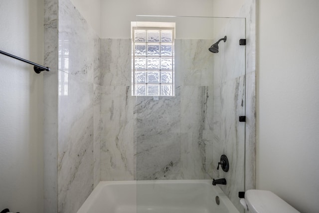 bathroom featuring toilet and tiled shower / bath