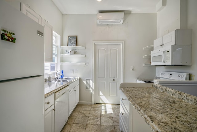 kitchen featuring light stone countertops, a wall mounted air conditioner, white cabinets, and white appliances