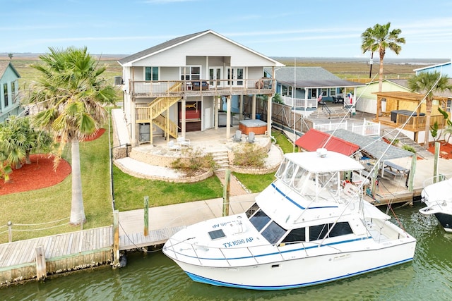 rear view of property with a lawn, a patio area, and a deck with water view